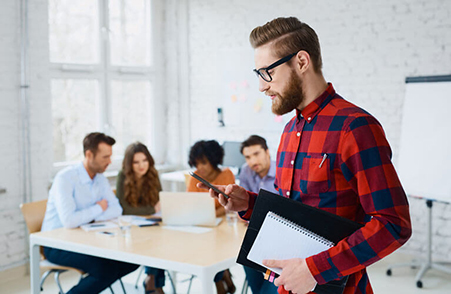 Male employee working on mobile app along with his team members